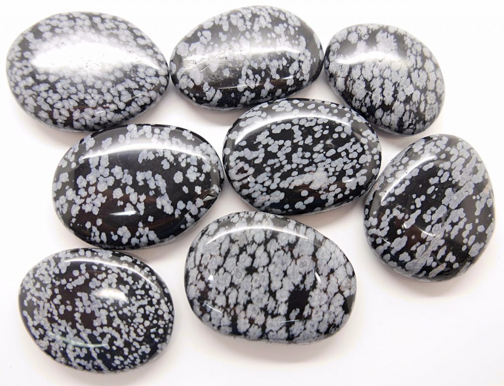 Obsidiana nevada rodada en primer plano mostrando su brillo plateado y tacto pulido