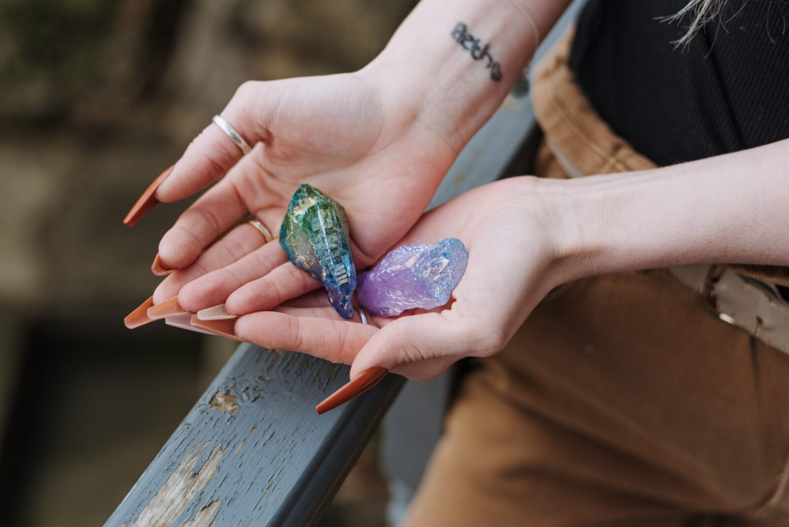 Los 10 cristales más poderosos para la meditación 11 From above of faceless female demonstrating colorful uncut opals in hands while standing near shabby wooden railing on blurred background